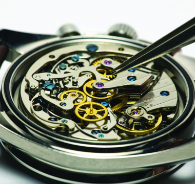 Inside of an automatic watch being repaired with tweezers.