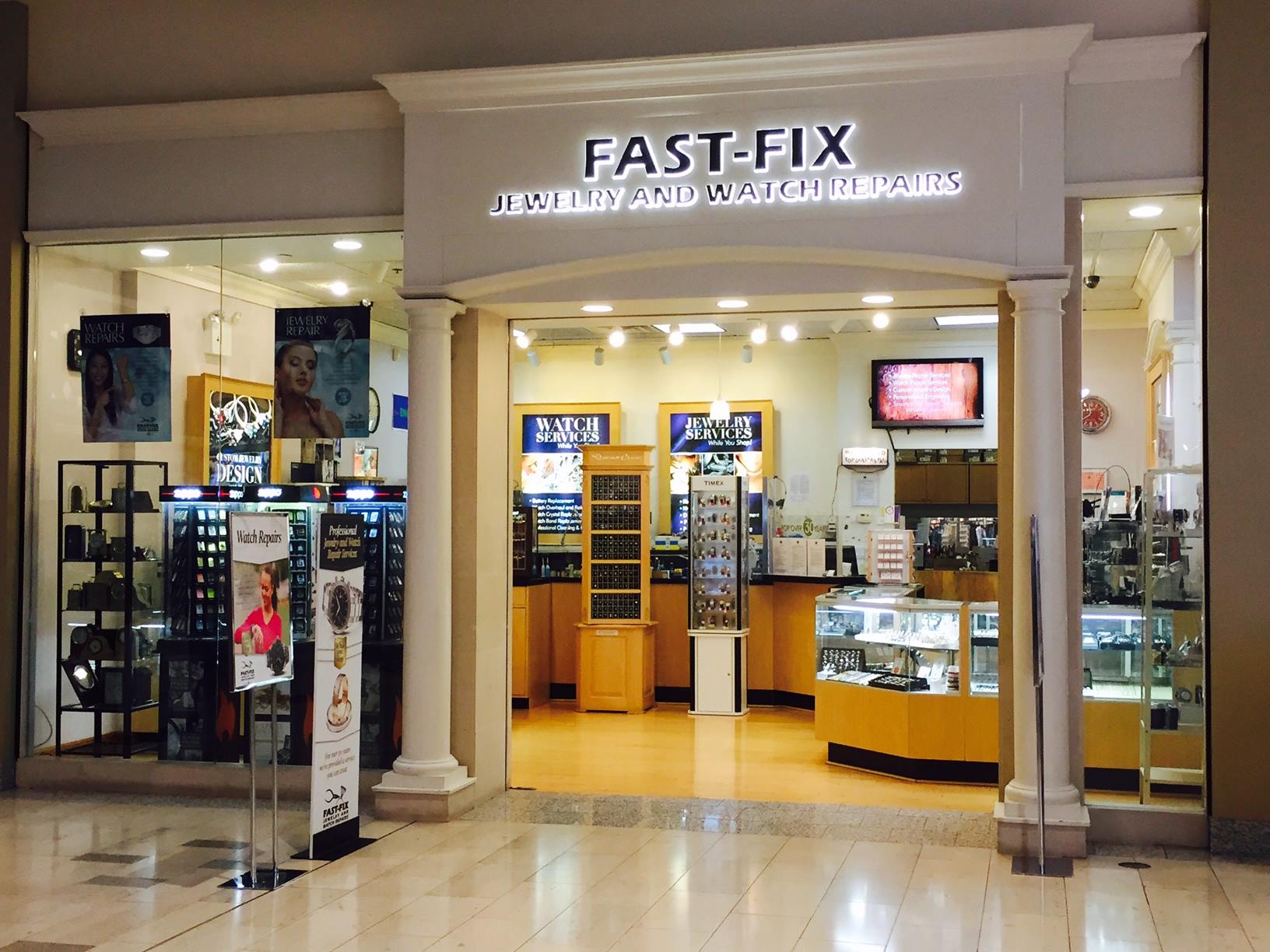 Store front of a Fast Fix Jewelry and Watch Repairs store at Staten Island Mall. Shows 2 white pillars with glass walls showing the interior of the store