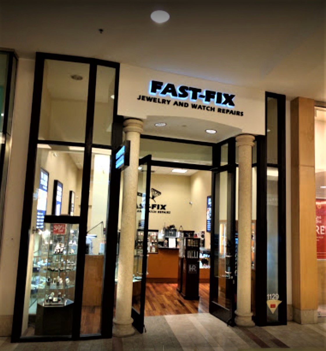 Picture of Fast-Fix storefront at South Center Mall. Two pillars with Fast-Fix Jewelry and watch Repairs logo on top. Windows on the sides that let the customer see through the store.