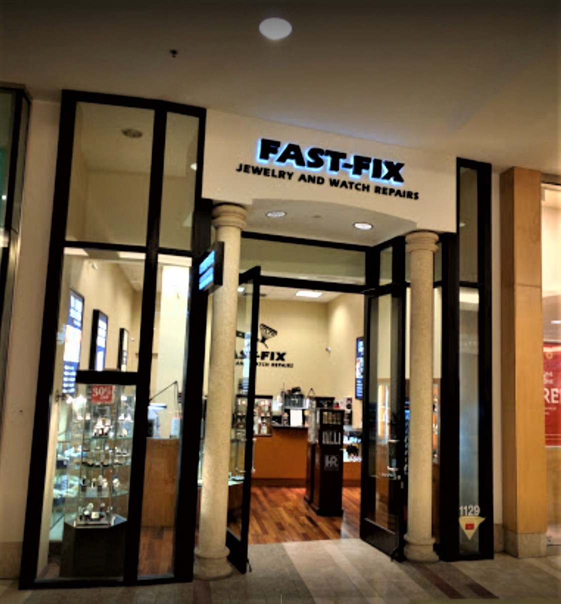 Storefront of Fast-Fix store at South Center Mall. 2 main pillars with logo on top and windows on the sides that let the customer see through the store
