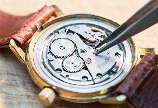 A gold watch with brown leather band appears open and you can see the mechanics of it.